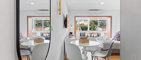 A modern hotel room with a dining area, a large mirror, and a view of the outside.
