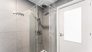 A glass-enclosed shower with a handheld showerhead and a wall-mounted faucet. - GuestReady - Bright Studio in Bonfim District (Porto)