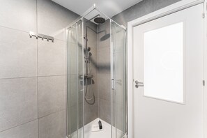 A glass-enclosed shower with a handheld showerhead and a wall-mounted faucet. - GuestReady - Bright Studio in Bonfim District (Porto)