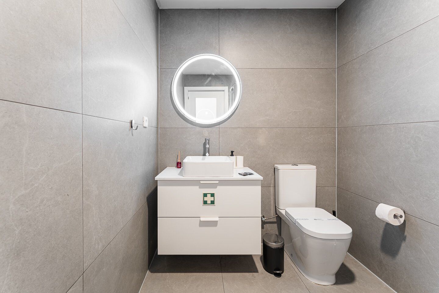Un baño moderno con inodoro, lavamanos y espejo.