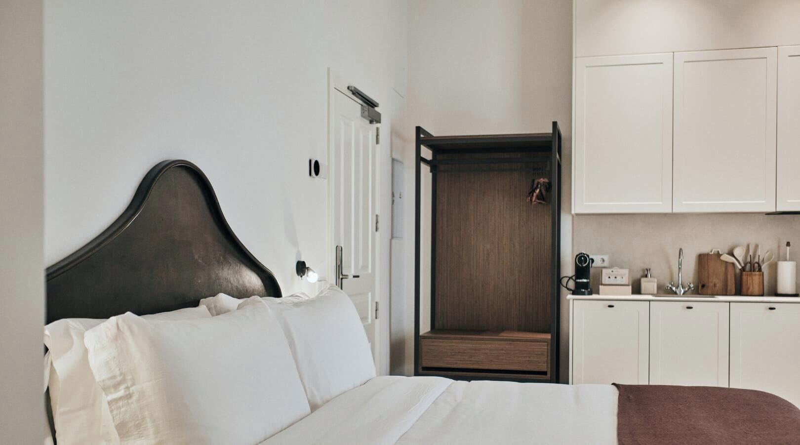 Une chambre d’hôtel comprenant un lit, une armoire, un petit coin salon et une kitchenette.