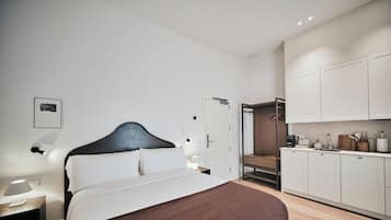 A modern bedroom with a bed, bedside table, and a nightstand. There is a wardrobe with a mirror and a door leading to a bathroom.