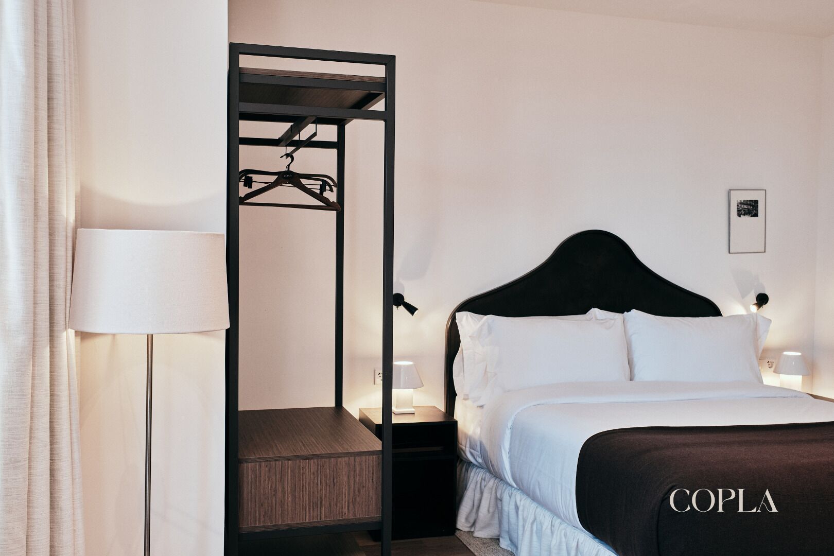 Een hotelkamer met een bed, een kledingkast, een nachtkastje en een lamp.