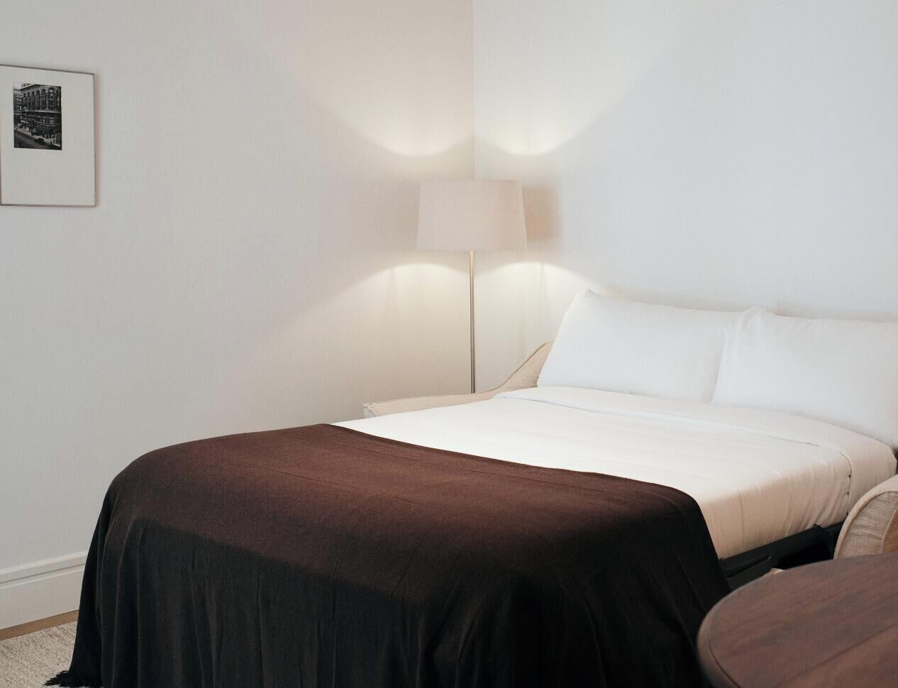 Une chambre d’hôtel avec un lit, une lampe de chevet et un tableau encadré au mur.