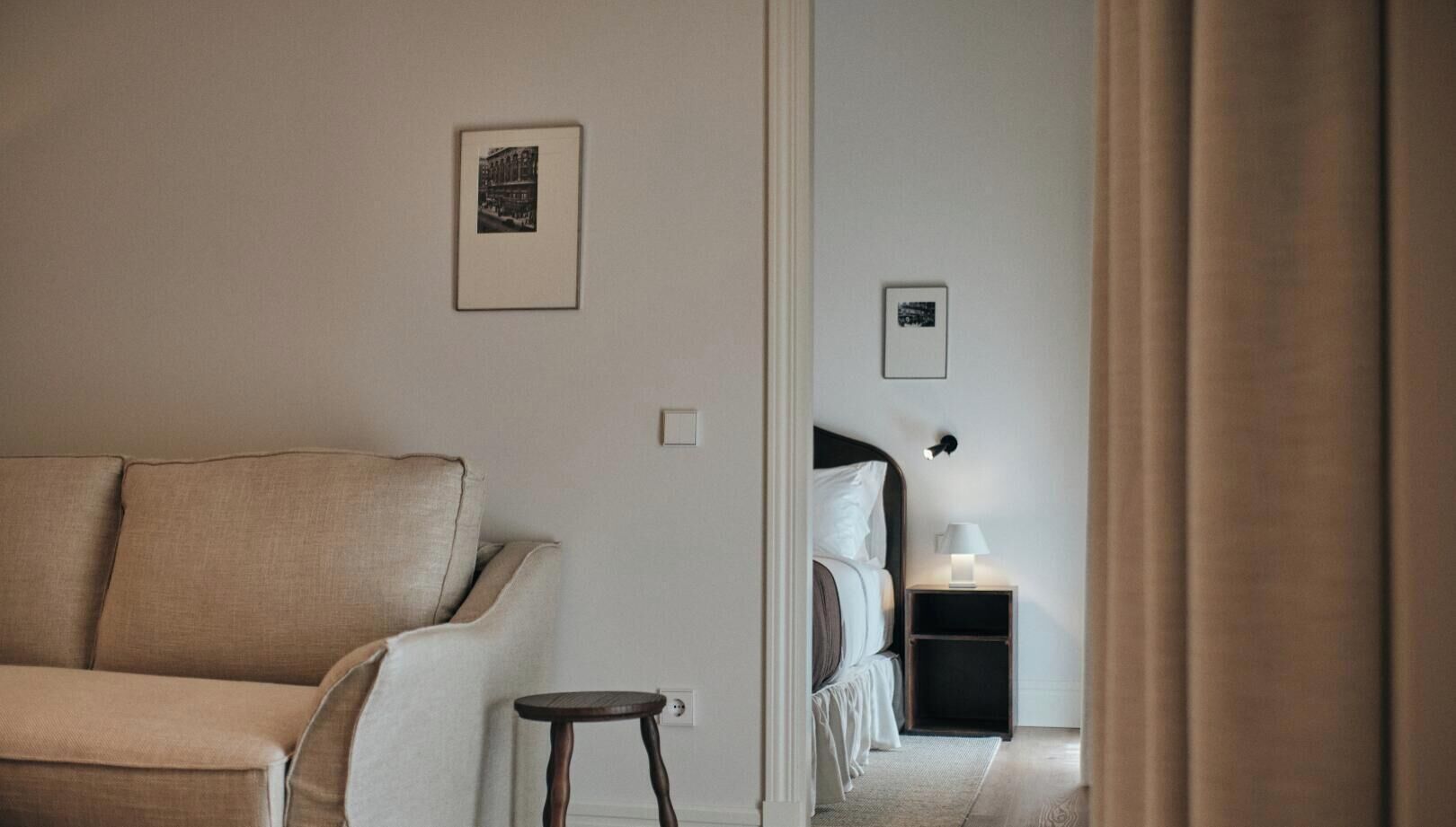 Una habitación con sofá, mesita de noche, lámpara y cama.