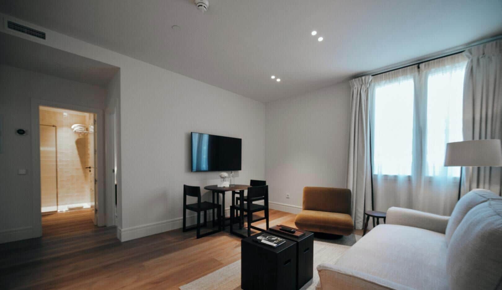 Una sala de estar moderna con una televisión de pantalla plana, un sofá, una mesa de centro y un sillón.
