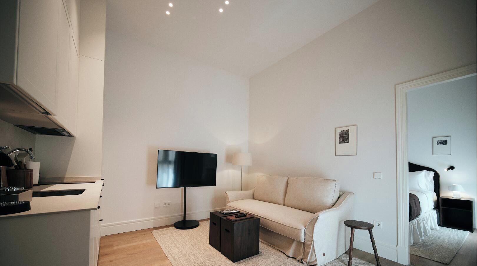 A modern living room with a flat-screen TV, a sofa, a coffee table, and a small side table.