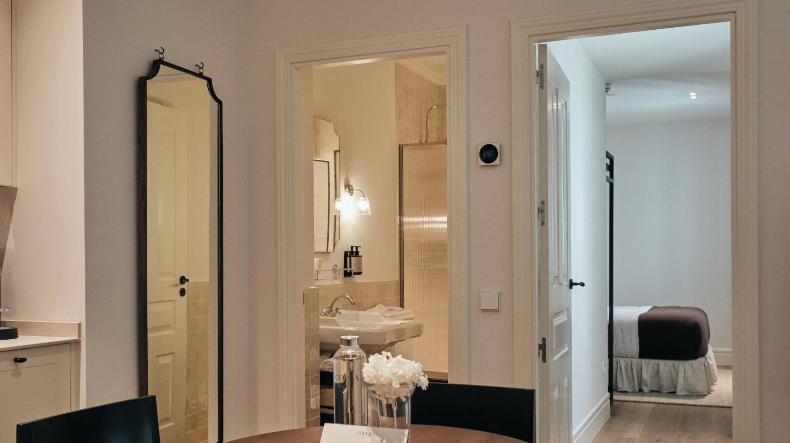 Una habitación de hotel con baño, zona de comedor con mesa y sillas, y una cama.