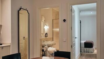 Una habitación de hotel con baño, zona de comedor con mesa y sillas, y una cama.