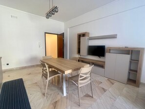 Una cucina moderna con zona pranzo, TV integrata e mobiletto in legno.