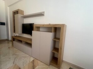 A modern entertainment unit with a flat-screen TV, wooden shelves, and a marble-patterned floor. - 50 meters from the museum and the main street (Reggio Calabria)