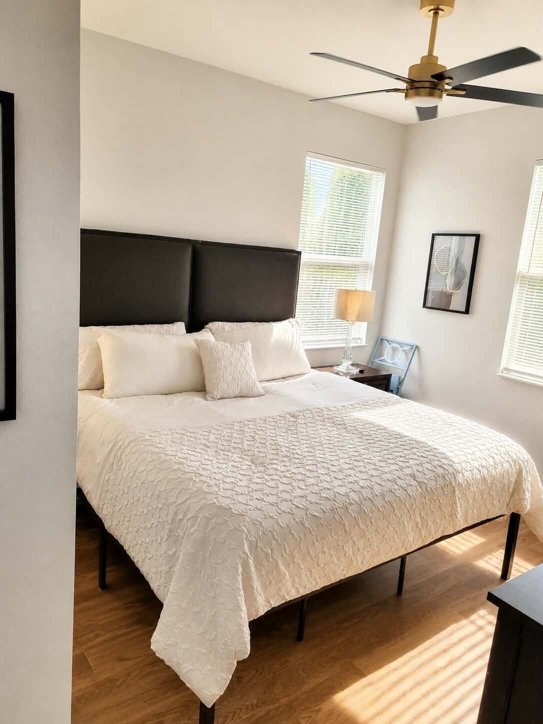 Un dormitorio con una cama grande, un ventilador de techo y una mesita de noche con lámpara.