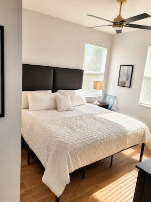 Ein Schlafzimmer mit einem großen Bett, einem Deckenventilator und einem Nachttisch mit Lampe.