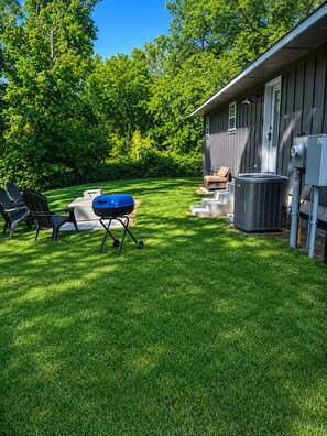 A backyard with a grill, chairs, and an air conditioning unit. -     Luxury 2BR Retreat Near Turner Falls & Cross Bar (Davis)