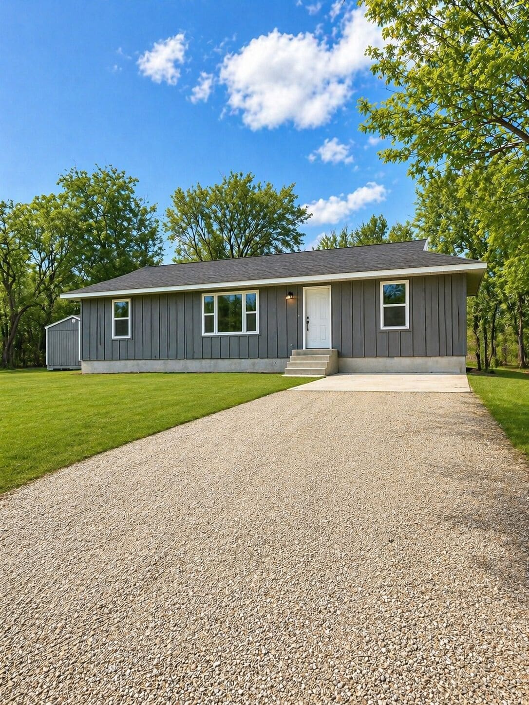A single-story house with a gravel driveway and a well-maintained lawn.