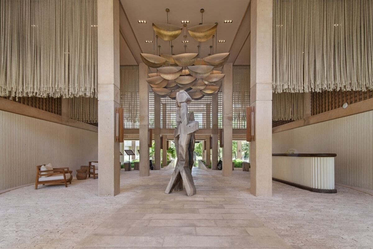A spacious lobby with a central sculpture, high ceilings, and a reception desk.