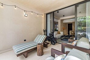A modern living room with a sofa, a striped chair, a wooden stool, and a motorcycle. - Yáax K'iin: Poolside Oasis + Free E-Bikes (Playa del Carmen)