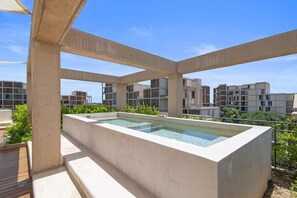 A rooftop pool area with a rectangular pool, surrounded by concrete structures and greenery. - Yáax K'iin: Poolside Oasis + Free E-Bikes (Playa del Carmen)