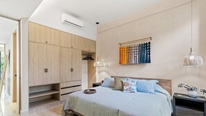 Ein Schlafzimmer mit Bett, Kleiderschrank, Vorhängen und Pendelleuchten.
