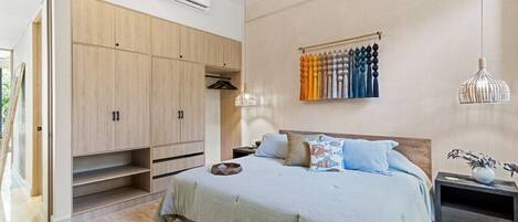 A bedroom with a bed, wardrobe, hanging curtains, and pendant lights.