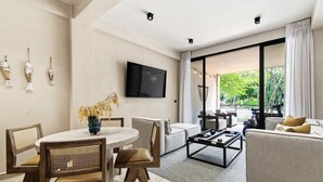 Ein modernes Wohnzimmer mit Essbereich, einem an der Wand montierten Flachbildfernseher und einer großen Schiebeglastür, die zu einem Außenbereich führt.