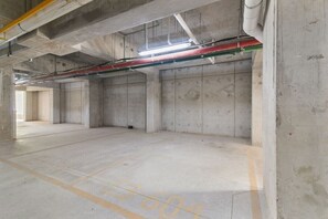 An empty parking garage with concrete walls and floors, and visible utility pipes and cables. - Túumben: Penthouse Unit w/ Spectacular Ocean & Golf Views (Playa del Carmen)