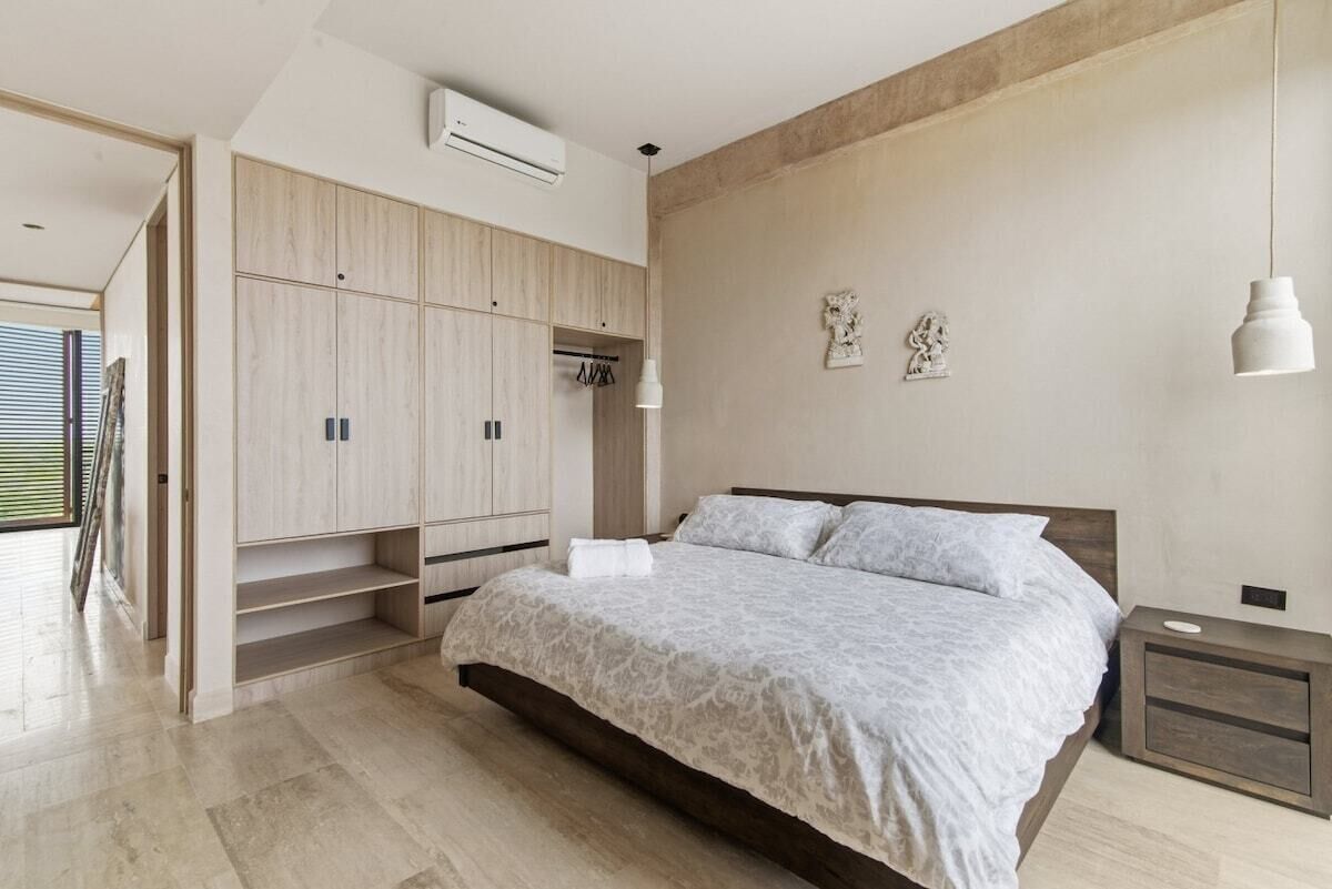 Een slaapkamer met een bed, een kledingkast, een nachtkastje en een hanglamp.