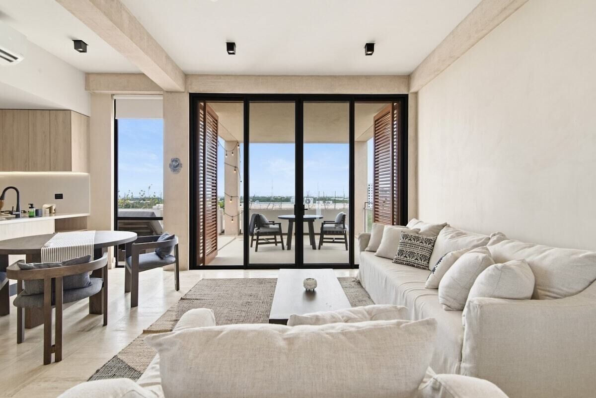 A modern living room with a sofa, a coffee table, and a dining area with chairs and a table.