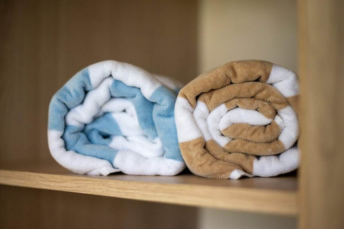 Kaksi rullattua peittoa puisella hyllyllä.