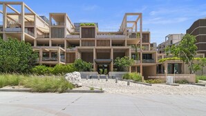 A multi-story residential building with balconies, a central courtyard, and a modern architectural design. - Penthouse Unit w/ Spectacular Ocean & Golf Views (Playa del Carmen)