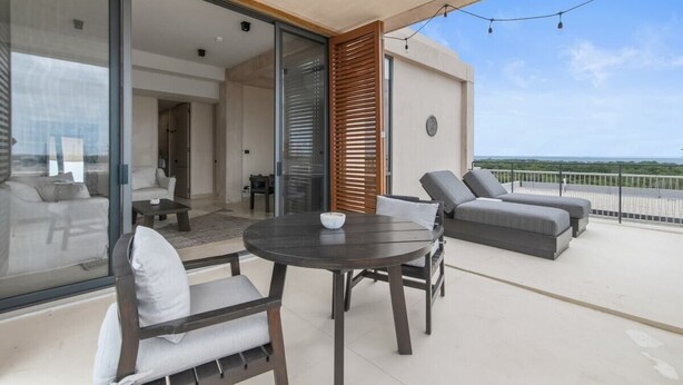 A balcony with a round table and chairs, a sofa, and a view of the sea. - Penthouse Unit w/ Spectacular Ocean & Golf Views (Playa del Carmen)
