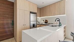 A modern kitchen with a central island, built-in appliances, and wooden cabinetry. - Penthouse Unit w/ Spectacular Ocean & Golf Views (Playa del Carmen)