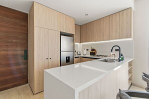 A modern kitchen with a central island, built-in appliances, and wooden cabinetry. - Penthouse Unit w/ Spectacular Ocean & Golf Views (Playa del Carmen)