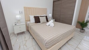 Ein Hotelzimmer mit einem großen Bett, einem Nachttisch mit Lampe, einer Topfpflanze und einer Schiebetür.