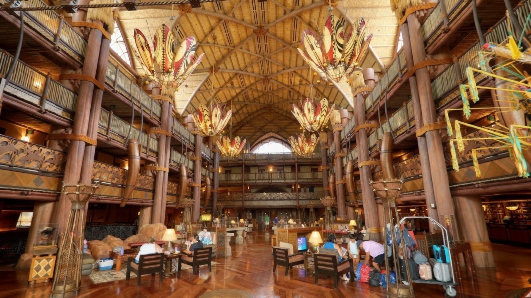 A spacious lobby with high wooden ceilings and intricate carvings, featuring multiple seating areas and a central reception desk.