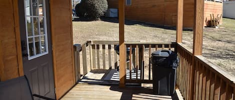 A wooden deck with a railing, a bench, and a trash can.