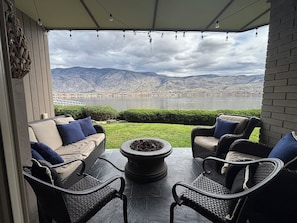 A patio with outdoor furniture, a fire pit, and a view of a lake and mountains.