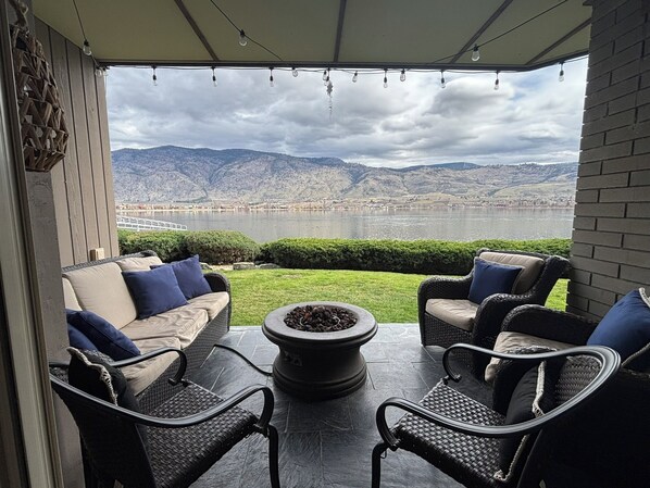 A patio with outdoor furniture, a fire pit, and a view of a lake and mountains.