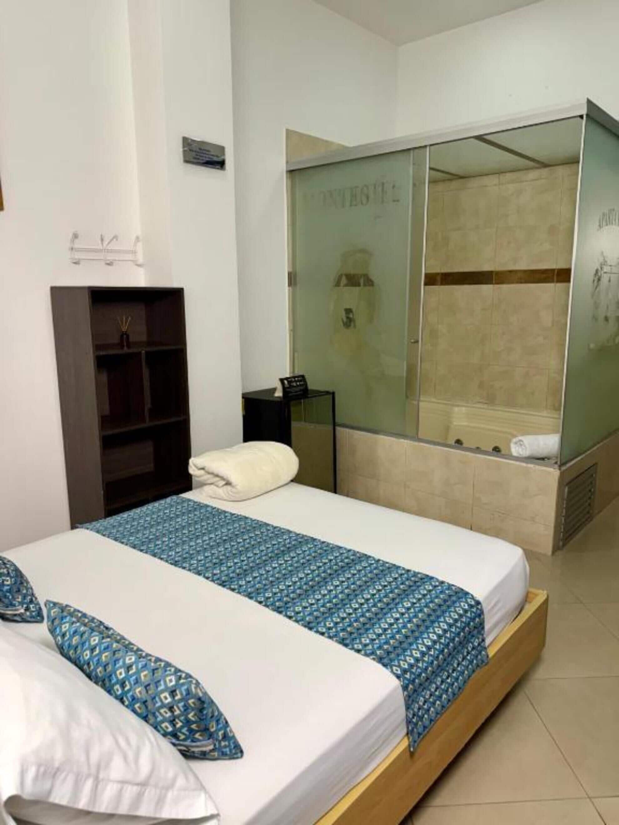 Une chambre d’hôtel comprenant un lit, une armoire, une petite table et un espace douche.