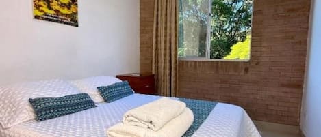 Una habitación de hotel con una cama grande, una ventana con cortinas, una pared de madera y un cartel en la pared.