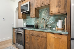 A kitchen with a built-in oven, a stove, a microwave, and wooden cabinets. - Luxury Capitola Retreat | Hot Tub | Blocks to Sand (Capitola)