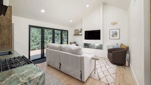 A modern living room with a sofa, a TV, and a fireplace. - Luxury Capitola Retreat | Hot Tub | Blocks to Sand (Capitola)