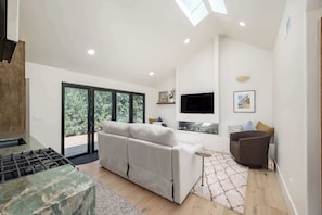 A modern living room with a sofa, a TV, and a fireplace. - Luxury Capitola Retreat | Hot Tub | Blocks to Sand (Capitola)