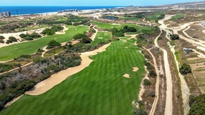 An aerial view of a golf course with multiple greens, sand bunkers, and a coastal backdrop. - Beachfront King Studio at Diamante Dunes (Cabo San Lucas)