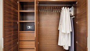 A wooden wardrobe with a safe, a hanging rack, and a robe. - Beachfront King Studio at Diamante Dunes (Cabo San Lucas)