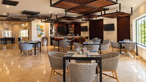 A spacious dining area with high ceilings, exposed beams, and a bar with a variety of bottles. - Beachfront King Studio at Diamante Dunes (Cabo San Lucas)