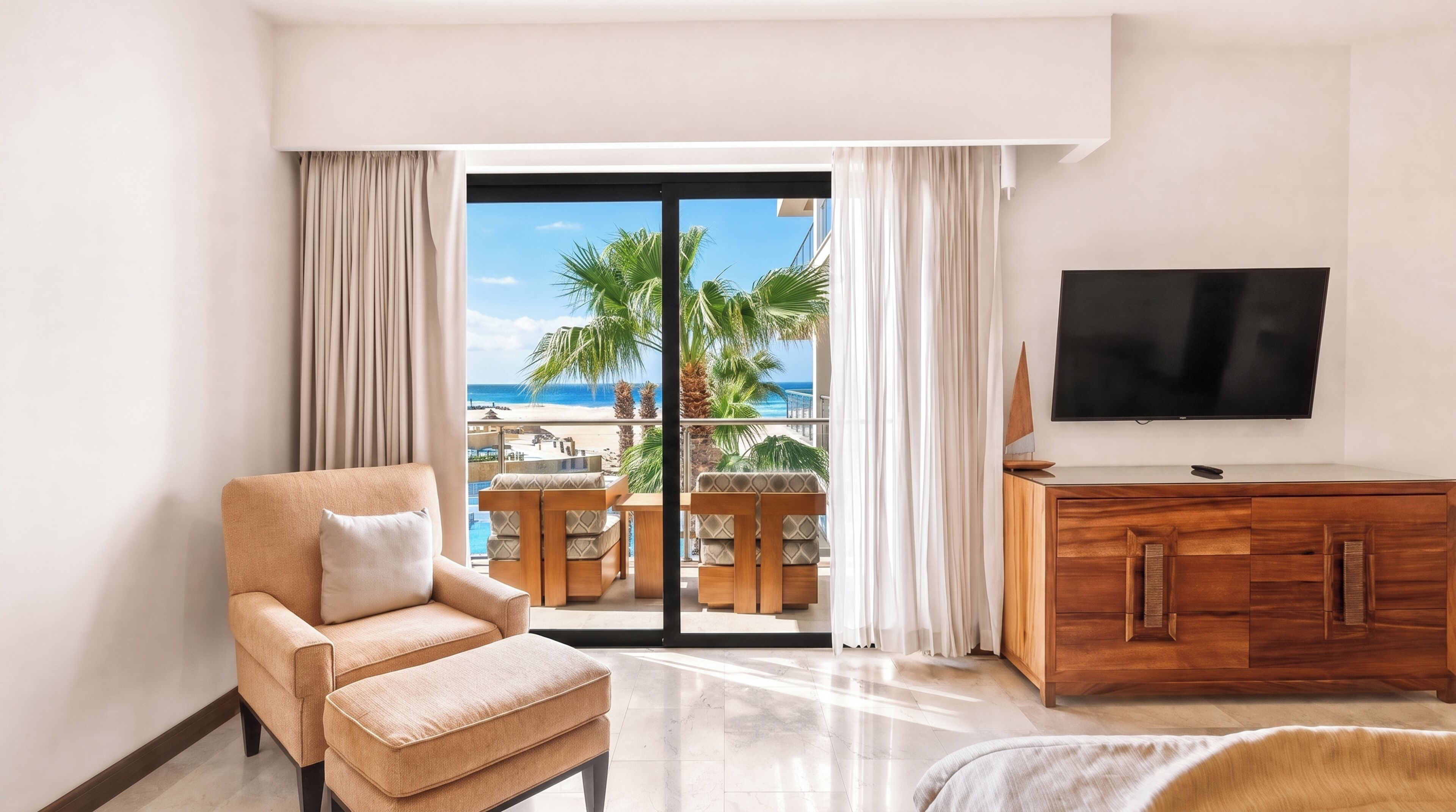 Habitación de hotel con balcón, televisor, sofá y mueble de madera.