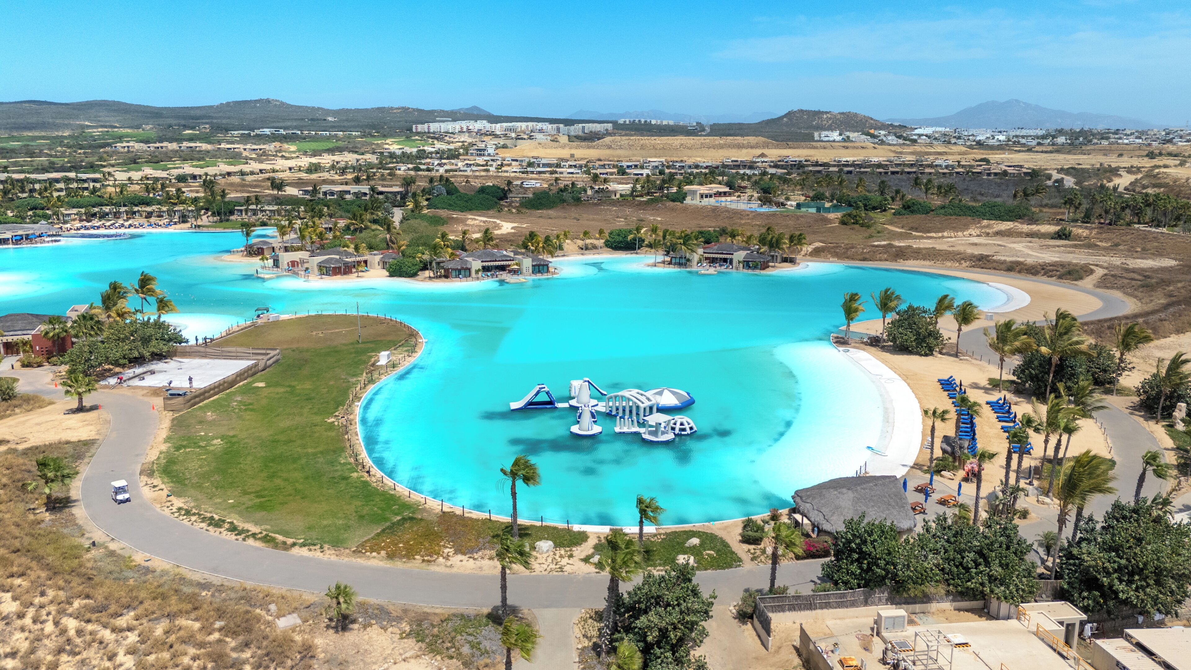 A resort with multiple swimming pools, a road, and surrounding greenery.