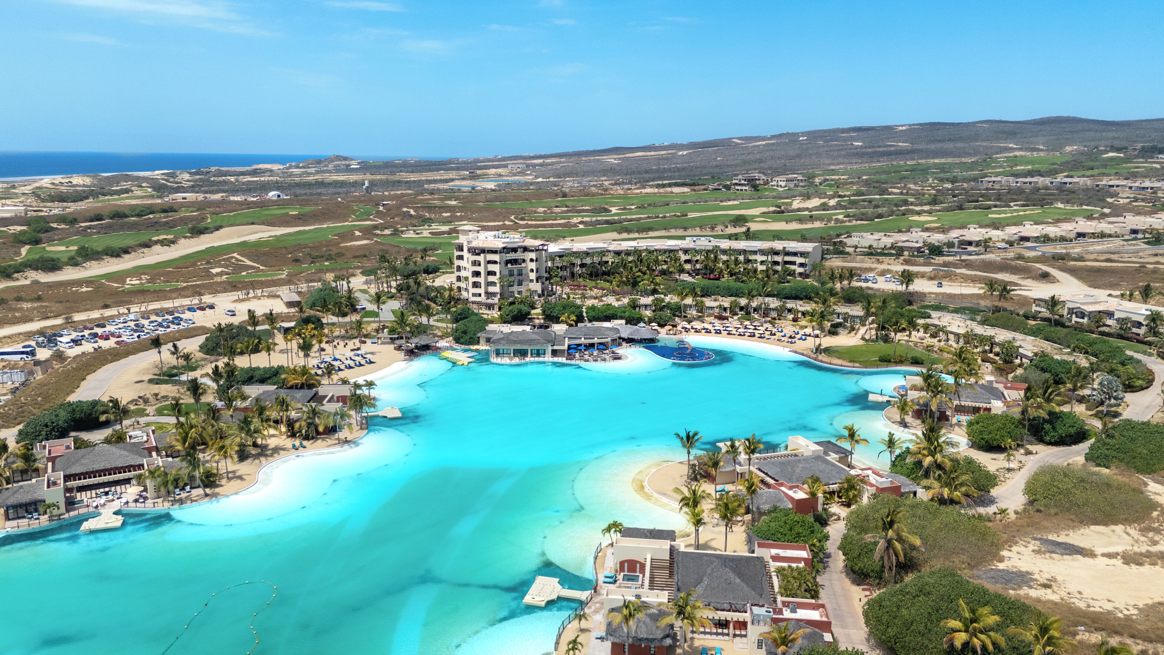 Un resort con una piscina grande, acceso directo a la playa y varias edificaciones.