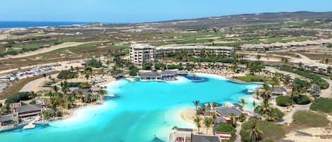 Un resort con una piscina grande, acceso directo a la playa y varias edificaciones.
